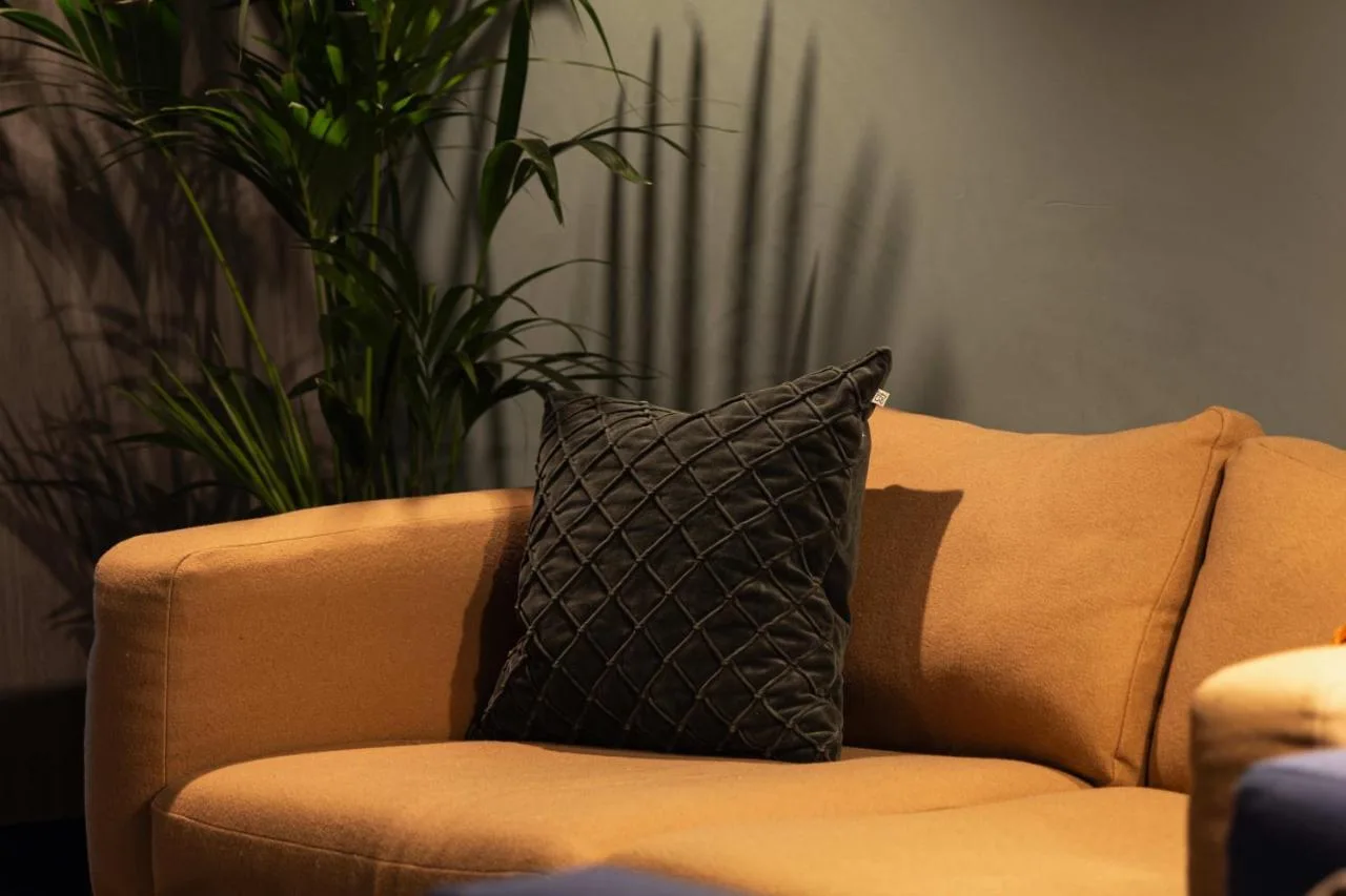 a black pillow sitting on a couch with a plant at Cove Minshull Street in Manchester